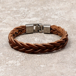 Brown braided leather bracelet with vintage silver metal buckle on stone background