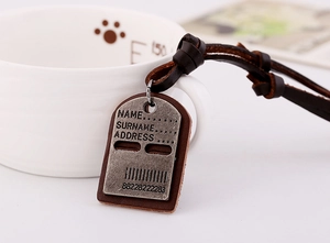 Detail of vintage metal luggage tag with brown leather backing and engraved text