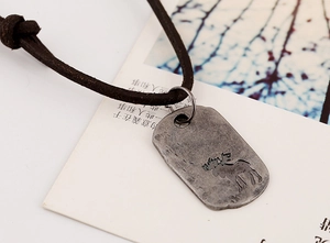 Macro view of vintage alloy elk pendant on genuine leather cord necklace with rustic finish