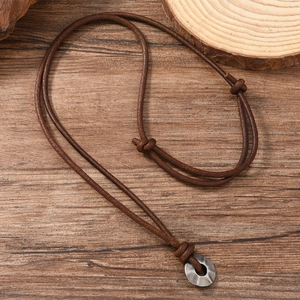 Retro adjustable brown leather necklace featuring a hammered silver metal pendant on wood