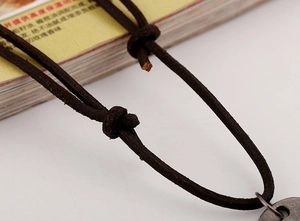 Close-up of adjustable knot on dark brown leather necklace cord with vintage texture