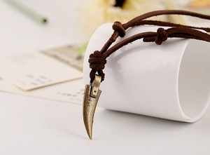 Macro detail of retro bronze claw pendant on dark brown adjustable leather cord