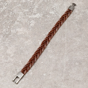 Close-up of brown braided leather bracelet with grey gold metal magnetic clasp on stone