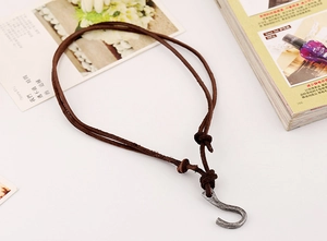 Macro detail of retro S-hook pendant with dark brown leather braided cord for men