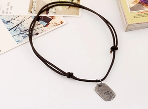 Close-up of vintage metal reindeer pendant on a dark brown leather cord necklace