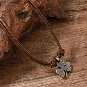 Macro view of vintage shamrock pendant on brown leather cord over a rustic wood surface