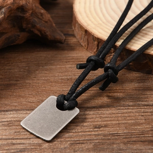 Macro detail of vintage cross pendant on adjustable black cord with leather texture