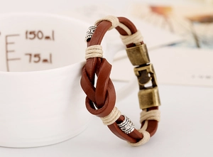 Détail du bracelet en cuir tressé vintage avec perles argentées sur céramique blanche