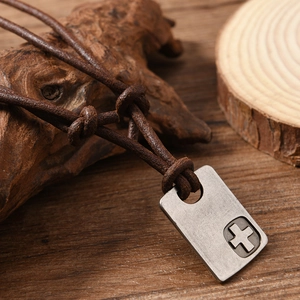 Detail of vintage rectangular metal cross pendant on adjustable dark brown leather cord