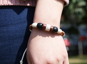 Close-up of braided leather bracelet with black beads and white woven cotton rope