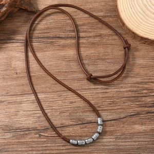 Vintage adjustable brown leather necklace with textured silver beads on wooden base