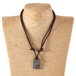 Detail of vintage cross pendant on brown leather cord shown on a mannequin bust