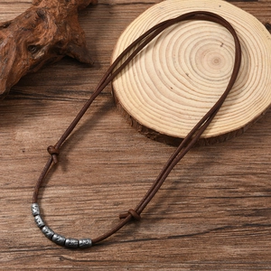 Detail of vintage adjustable brown leather necklace with textured silver beads on wood