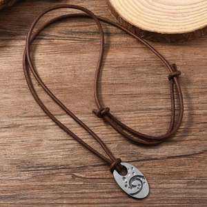 Men's retro leather necklace with textured oval metal pendant on a dark wood background