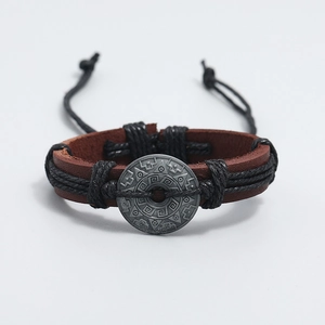 Macro view of woven leather bracelet with ethnic metal totem and adjustable cord
