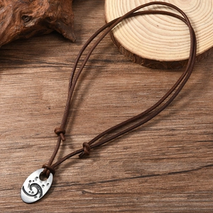 Close-up of vintage brown leather necklace with engraved silver oval spiral pendant
