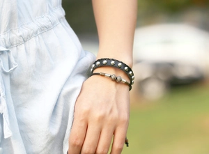 Nahaufnahme eines schwarzen Punk-Lederarmbands mit Nieten und Vintage-Perlenschnur