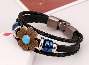 Detail of a multilayer leather bracelet with a bronze flower and blue stone inlay