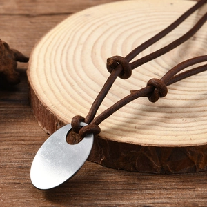 Retro men's cowhide leather necklace with oval matte metal pendant on wood surface