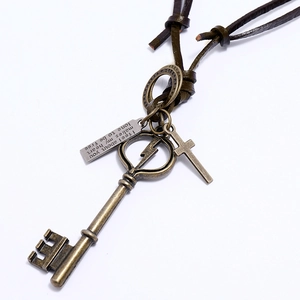 Dettaglio di ciondoli a chiave e croce vintage su una collana lunga in pelle marrone