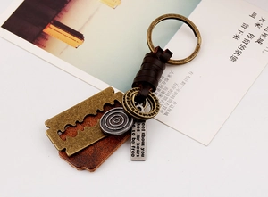 Close-up of vintage bronze razor blade pendant with braided leather on metal keychain