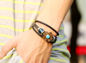 Detailed close-up of a multi-layer leather bracelet with vintage sunflower metal charm