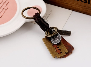 Detail of vintage braided leather keychain with quote plate and blade pendant