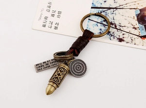 Macro shot of vintage bronze bullet charm and engraved metal tag on woven leather keychain