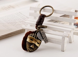 Detail of vintage bronze African mask keychain with engraved metal tag and leather wrap