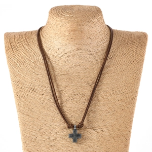 Detail of vintage metal cross pendant on braided brown leather cord shown on a bust