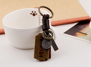 Detail of vintage braided leather keychain with bronze alloy blade and engraved charms