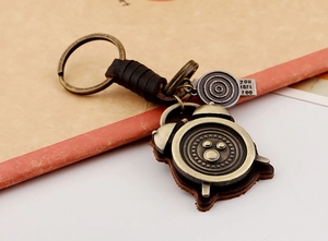 Detail of vintage leather keychain with bronze clock pendant and engraved metal tag