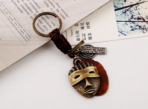 Detail of vintage skull mask keychain with braided brown leather and engraved metal tag
