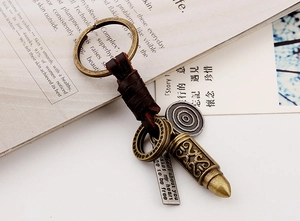 Close-up of vintage braided leather keychain with bronze bullet pendant and metal tags