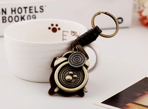 Detail of vintage bronze alarm clock pendant on dark brown woven leather keychain