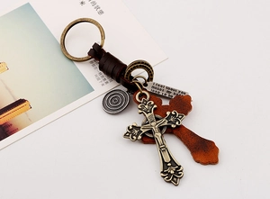 Vue macro d'un porte-clés croix en bronze vintage avec gravure et lanière en cuir tressé