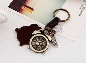Detail of vintage bronze alarm clock pendant and engraved leather keychain charm