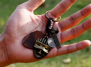 Close-up of vintage bronze tribal mask pendant and engraved leather keychain