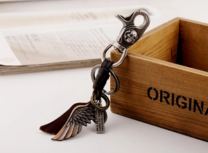 Detailed close-up of retro leather keychain with metal wing pendant and skull buckle