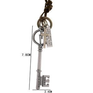 Collana in pelle retrò con ciondolo a chiave vintage e charm incisi su sfondo bianco