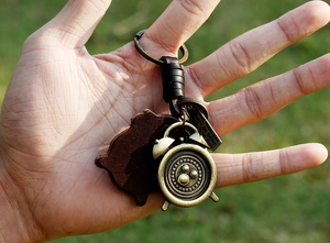 Macro detail of retro bronze clock pendant and dark brown leather key ring with engraving