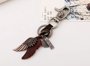Macro view of vintage leather keychain with bronze wings and motivational metal plate