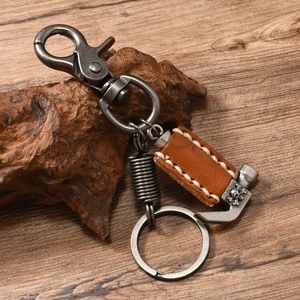 Retro punk keychain with brown leather wrap and skull hammer pendant on a wooden surface