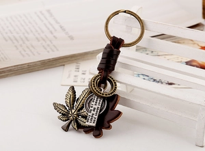 Detail of vintage woven leather keychain with bronze maple leaf and engraved metal tag