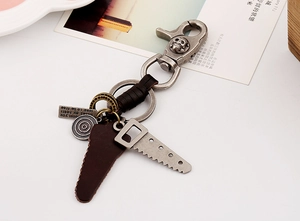Detail of vintage leather keychain with alloy saw pendant and skull carabiner hook