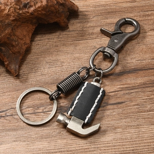 Detail of a vintage punk hammer pendant keychain with leather wrap on dark wood background