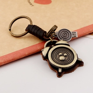 Vintage bronze alarm clock keychain with leather strap and metal charm on desk