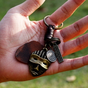 Vintage bronze tribal mask leather keychain with engraved pendant on a woven strap