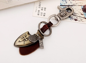 Macro detail of vintage leather keychain with bronze skull clip and shield pendant