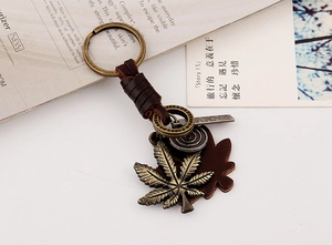 Detail of retro leather keychain with bronze maple leaf pendant and woven strap